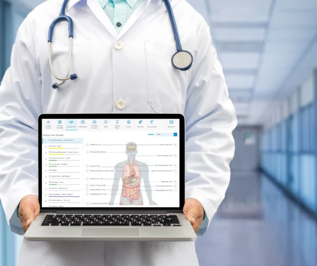 photo of a health care professional in a white laboratory coat and a stethoscope around his neck holding a lap top computer and on the screen shows the results of a body energy scan