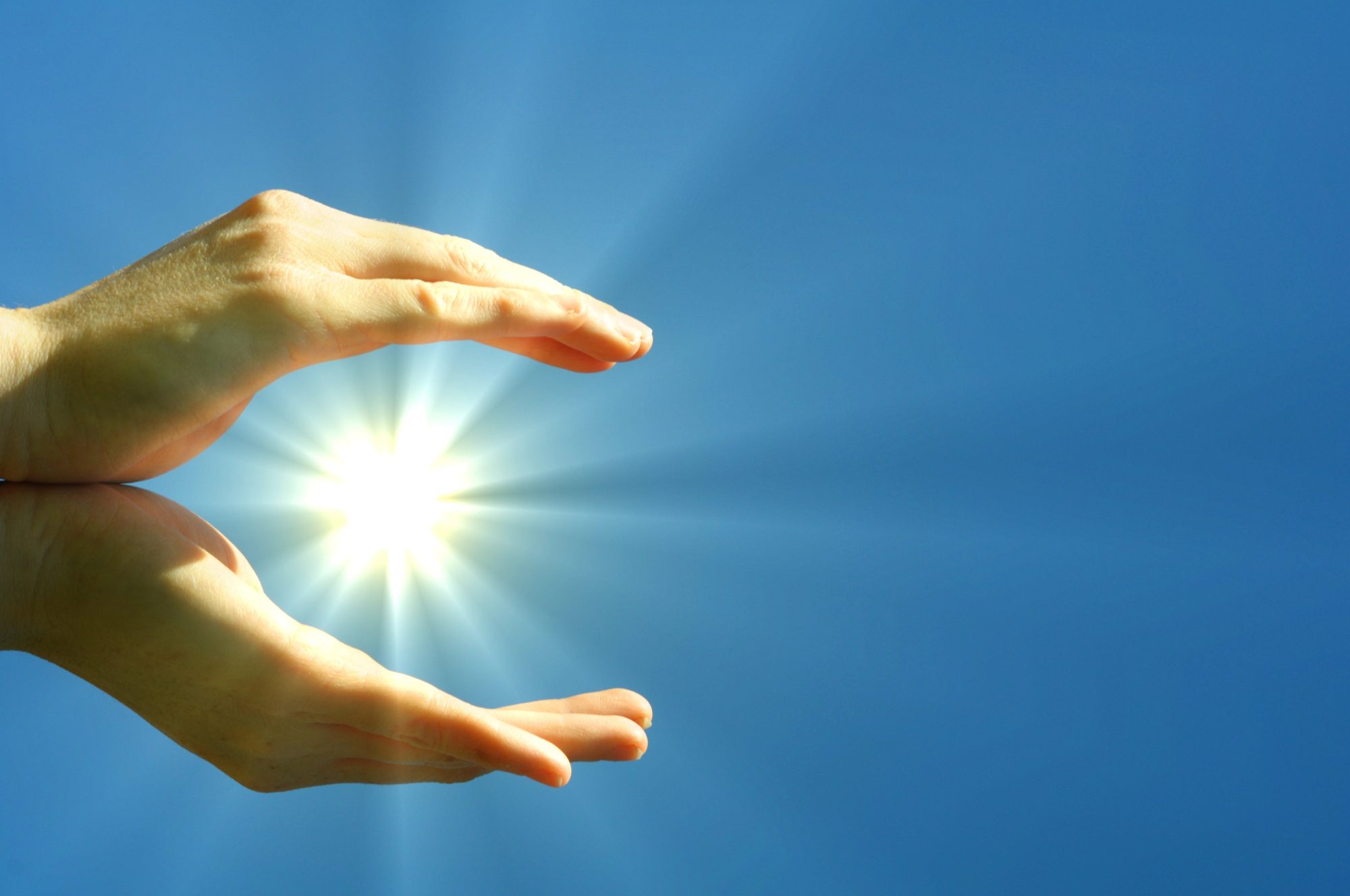 palms open and facing each other with a light ball of energy in between, white light, with a sky blue background