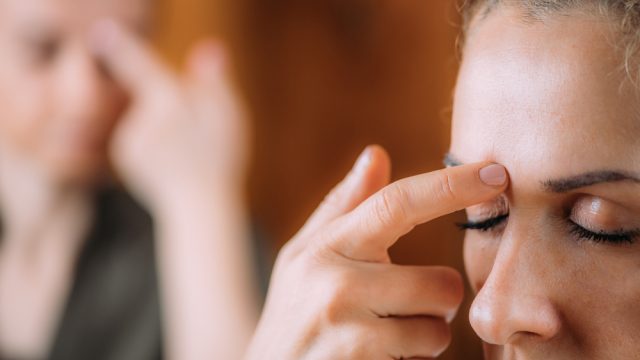 photo of a two women doing the emotional freedom technique,tapping the eyebrow meridian point with their index fingers.